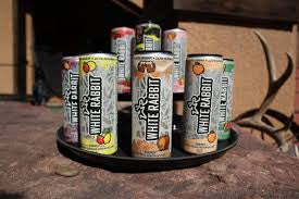Assorted cans of White Rabbit Energy on a tray with a deer head in the background.