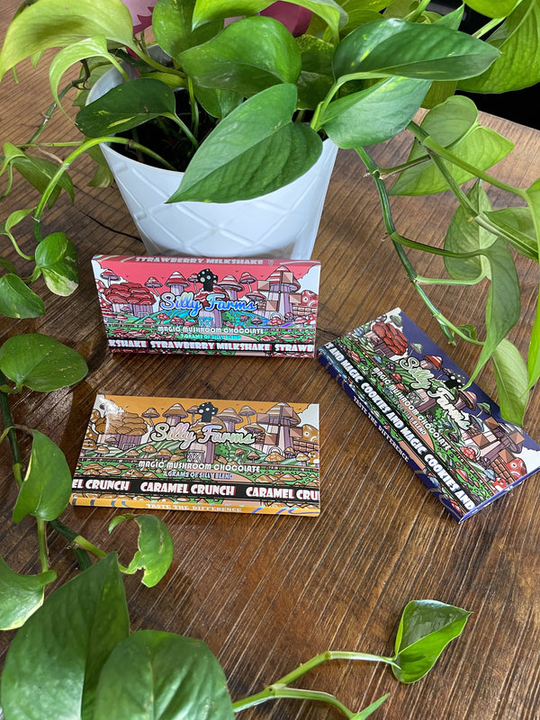 Three boxes of candy on a wooden surface with green plants around