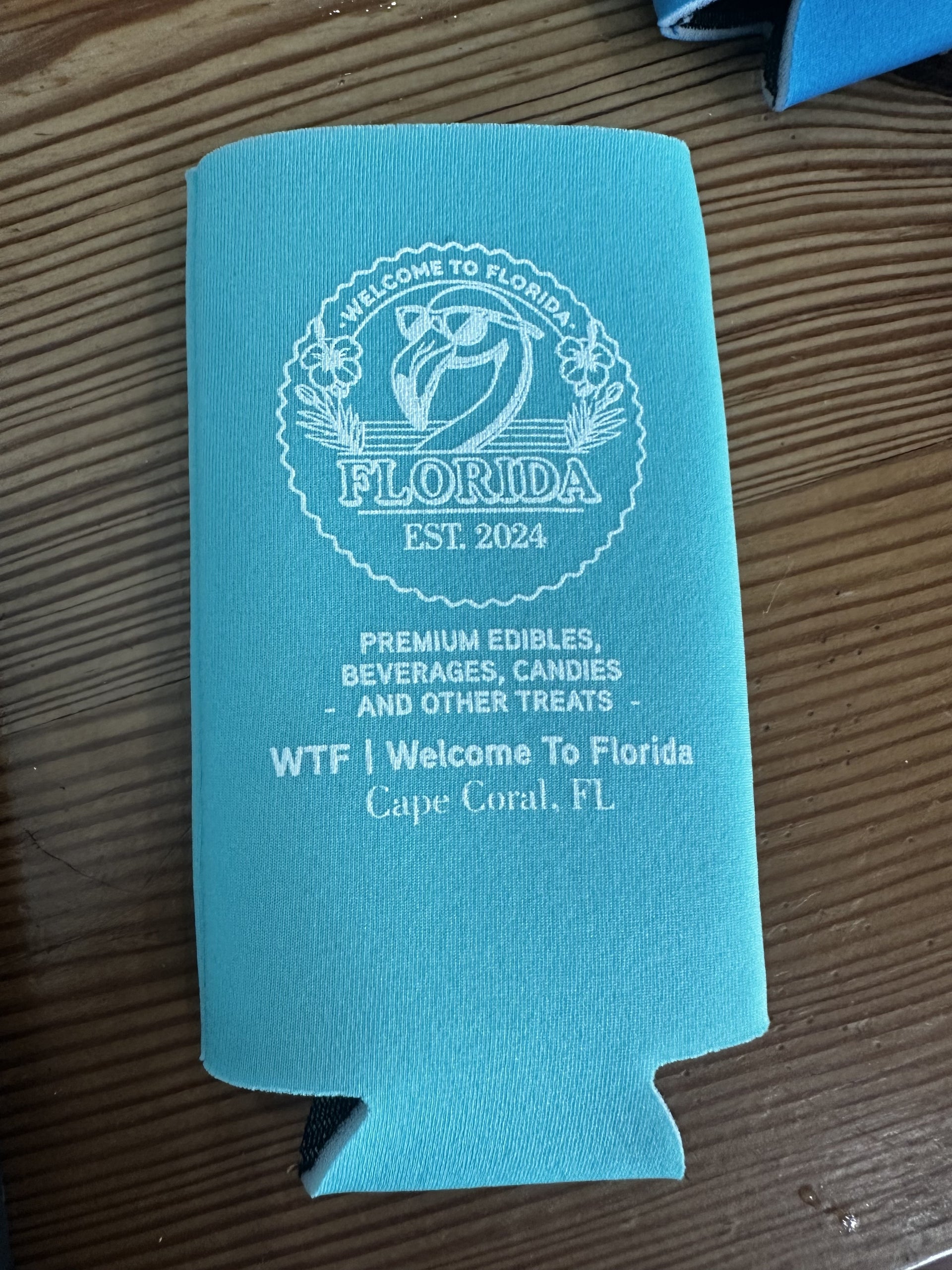Teal can cooler with 'Welcome to Florida' text on a wooden surface
